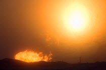 The winter sun setting behind a gas flare a drilling site near Sabetta, South Tambey Gas Field, Yamal Peninsula, Siberia, Russia. February 2014.