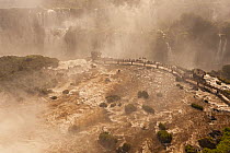 Landscape of Iguazu Falls in mist, with  tourists on viewing platform, Iguazu Falls, Iguazu National Park, Brazil, January 2014.