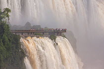 Iguazu Waterfalls and tourists on viewing platform, Iguazu Falls, Iguazu National Park, Brazil, January 2014.