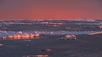 View from an icebreaker moving through an ice floe at sunset, Peterson Bank, Antarctica.