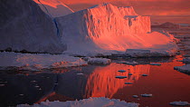 View of icebergs and pack ice at sunset, seen from a moving boat, Antarctica.