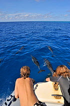 Children watching Spinner dolphins (Stenella longirostris) swimming with boat,  Mayotte. Indian Ocean. February 2010.