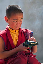 Young monk at Torgya festival with plastic toy gun. Galdan Namge Lhatse Monastery,Tawang, Arunachal Pradesh, India. January 2014.