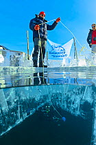 Support team on the surface of the ice helping diver below. Lake Baikal, Russia, March 2013.