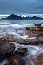 Waves washing up Elgol beach in the evening light with view of the Cuillins, Strathaird peninsula, Isle of Skye, Scotland, UK. December 2013.