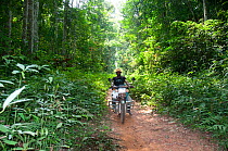 Man riding motorbike through the Ituri Rainforest, Democratic Republic of the Congo, Africa, December 2011.