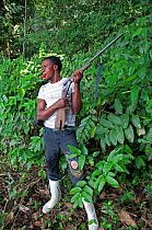 Mongo man with shotgun, and shot cartridge in mouth, Bomili Village, Ituri Rainforest, Democratic Republic of the Congo.
