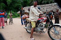 Mongo man at Bombili fish market on motorbike, Bombili Village, Ituri Rainforest, Democratic Republic of the Congo, December 2011.