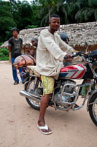 Mongo man at Bombili fish market on motorbike, Bombili Village, Ituri Rainforest, Democratic Republic of the Congo, December 2011.