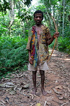 Mbuti Pygmy man, with bow and arrow. Arrows have iron tips and are used for hunting creatures on the ground. Those arrows without iron tips are used for shooting animals in trees, Ituri Rainforest. De...