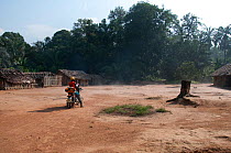 Mbuti Pygmy village, with non-pygmy man on motorbike, Democratic Republic of the Congo, Africa, January 2012.