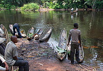 Men with dugout wooden canoes on riverbank, Monkoto, Salonga National Park, Equateur, Democratic Republic of the Congo, May 2012.