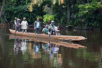 Local people crossing river in wooden dugout canoe, including man with goods on motorbike, Salonga National Park, Equateur, Democratic Republic of the Congo, May 2012.