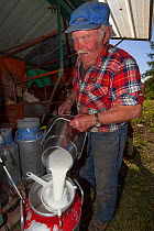 Farmer with milk to be sent to the Bourg-Saint-Maurice dairy for Beaufort cheese, Savoie, Rhone-Alpes, France, May 2014.