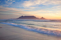 Wave washing over beach at sunset with table mountain in the background. Bloubergstrand, Cape Town, South Africa. November 2011. Non-ex.