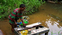 Woman standing in a river preparing a fish, Waka National Park, Gabon, 2008.