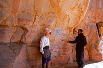 Guides pointing to ancient rock painting of pastoralists being attacked by horsemen, Guilemsi, central Mauritania, 2004.