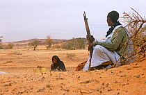 Guide holding gun,  with wife in Guilemsi, Mauritania, 2004.