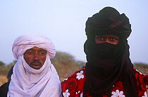 Two men, one with covered face, spectating at traditional Peul / Fula ceremony, Ngarawal Fuduk, near Agadez, Niger, 2005.