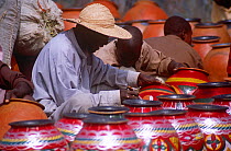 Man decorating pot at Mirriah pottery market, Niger, 2005.