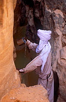 Toubou tribesman with drinking water found in rock formation. Northern Niger, 2005.