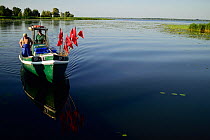 Fishermen in small boat on Stettiner Haff lagoon, Stepnica, Poland, July 2014.