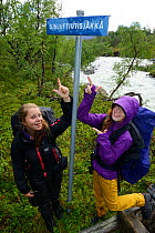 Two teenage girls pointing at sign post, on family hiking trip on the Laponia Circuit, along the Padjelantaleden trail, Padjelanta National Park and Sarek National Park, Norrbotten, Lapland, Sweden. M...