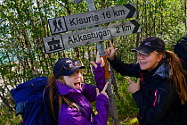 Two teenage girls standing by sign posts during hiking trip on the Laponia Circuit, along the Padjelantaleden trail, Padjelanta National Park, Norrbotten, Lapland, Sweden. Model released