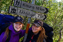 Two teenage girls standing by sign posts during hiking trip on the Laponia Circuit, along the Padjelantaleden trail, Padjelanta National Park, Norrbotten, Lapland, Sweden. Model released
