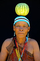 Portrait of Naro San woman wearing traditional clothing and headband, balancing gourd on head,  Kalahari, Ghanzi region, Botswana, Africa. October 2014.