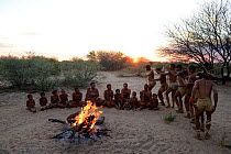 Naro San Bushmen family, men performing traditional dance and women singing and sitting around the fire at dawn. Kalahari, Ghanzi region, Botswana, Africa. Dry season, October 2014.