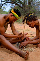 Naro San Bushmen making fire by rubbing stick, Kalahari, Ghanzi region, Botswana, Africa. Dry season, October 2014.