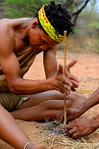 Naro San Bushman making fire by rubbing sticks, Kalahari, Ghanzi region, Botswana, Africa. Dry season, October 2014.