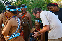 Photographer Eric Baccega showing pictures to Naro San women dancers wearing traditional clothing made with duiker leather. Kalahari, Ghanzi region, Botswana, Africa. Dry season, October 2014.