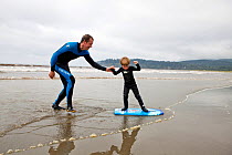 Nate Harrison teaching his son Gabriel how to surf, Hobuck Beach, Makah Reservation, Washington, USA, August 2014. Model Released. Model released.