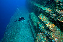 Diver examining the sandstone structure of the Yonaguni undersea monument, Yonaguni, East China Sea, Japan. February 2014.