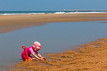 Young girl playing on the beach with a spade. Biarritz, Aquitaine, France, September 2014. Model released.