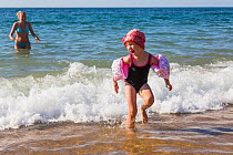 Young girl with armbands playing on beach in the surf. Biarritz, Aquitaine, France, September 2014. Model released.