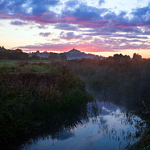 River Brue, at dawn with Glastonbury Tor in background,  Somerset, UK, August. Digital composite.