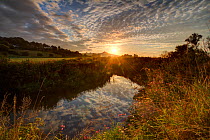 River Brue, at sunrise with Glastonbury Tor in background, Somerset, UK, August.