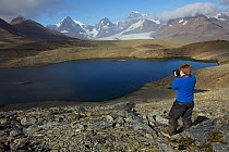 Russell Laman photographing Crean Lake on the hike between Fortuna Bay and Stromness, retracing part of Shackleton's route. South Georgia, February 2011. Model released.
