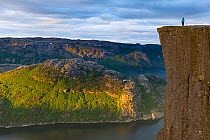 Person standing on The Preikestolen (Pulpit rock) at the Lysefjorden. Forsand, Rogaland, Norway, June 2012.