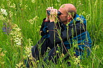 Birdwatcher with binoculars, Tarcu mountains nature reserve, Natura 2000 area, Southern Carpathians, Romania, May 2014.