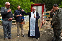 Armenis priest at the release of European bison / Wisent (Bison bonasus) in the Tarcu mountains nature reserve. The priest held a sermon for the bison and splashed them with Holy water. Natura 2000 ar...