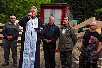 Armenis priest at the release of European bison / Wisent (Bison bonasus) in the Tarcu mountains nature reserve. The priest held a sermon for the bison and splashed them with Holy water. Natura 2000 ar...