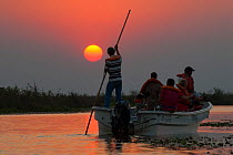 Tourists on boat on wildlife watching trip at sunset, Ibera Marshes, Corrientes Province, Argentina, July 2009.