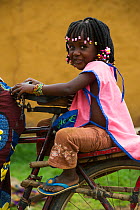 Young girl on back of bicycle, Mbomo Village, Odzala-Kokoua National Park, Republic of Congo (Congo-Brazzaville), Africa, May 2013.