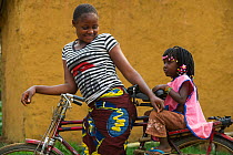 Local woman and girl on bicycle, Mbomo Village, Odzala-Kokoua National Park, Republic of Congo (Congo-Brazzaville), Africa, May 2013.