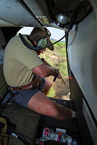 Vet in helicopter, preparing to dart Elephants (Loxodonta africana) for relocation to the reserve they had escaped from. Zimbabwe, November 2013.