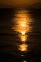 Sunset reflected on the surface of the Aegean Sea on a calm day, Evia Island, Greece. July 2014.